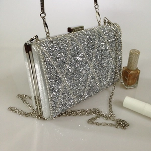 Close-up of silver sequined clutch bag with metal frame and elegant O-chain strap