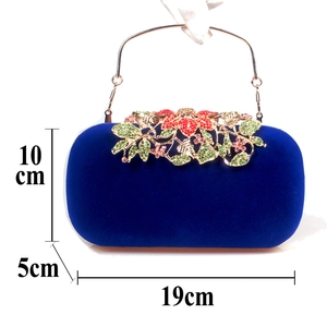 Macro shot of royal blue velvet evening bag with ornate floral crystal clasp and gold handle