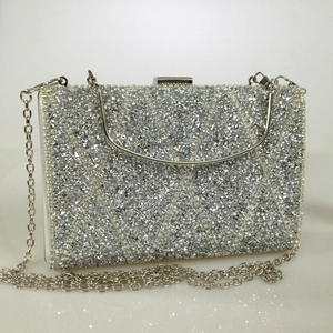 Detailed close-up of a silver clutch bag with sparkling crystals and diamond lattice pattern