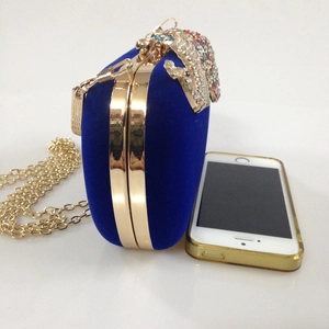 Detail of royal blue velvet clutch with gold frame and jeweled peacock clasp for size