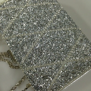 Close-up of sparkling silver rhinestone clutch with fine metal chain strap for evening