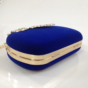 Detail of royal blue velvet evening bag with gold metal trim and sparkling crystal clasp