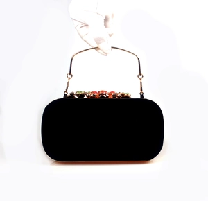 Detail of velvet evening clutch featuring colorful crystals and a gold handle