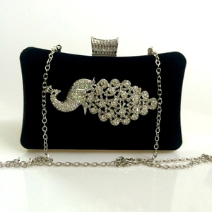 Macro detail of silver peacock rhinestone pattern on elegant black velvet evening clutch