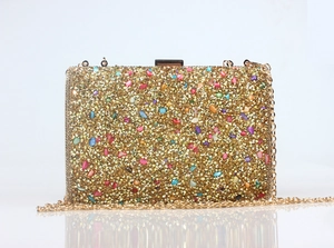 Detail of evening clutch bag featuring colorful stones and gold rhinestones with metal chain
