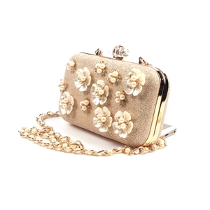 Detail of champagne gold evening clutch with 3D white flowers and pearl embellishments