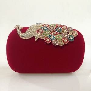 Detailed close-up of a luxury red velvet clutch featuring a colorful peacock rhinestone ornament