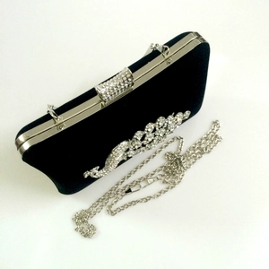 Detail of black velvet clutch with crystal peacock ornament and silver chain strap