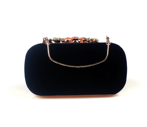 Macro shot of gold handle detail and multi-colored gemstone clasp on black velvet clutch