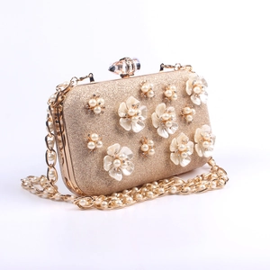 Macro shot of 3D pearl flower decor and crystal clasp on champagne glitter clutch