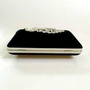 Macro view of black velvet evening bag with ornate silver peacock rhinestone decoration