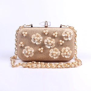 Detailed macro view of champagne gold evening bag with handmade pearl flowers and crystal clasp