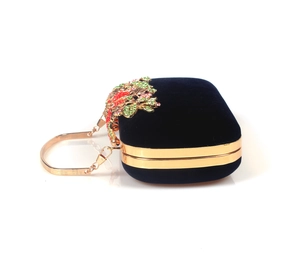 Close-up of luxury navy velvet clutch with golden leaf frame and colorful rhinestones
