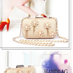 Detail of gold glitter clutch bag with 3D floral accents, pearls, and metal tassels
