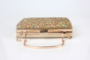 Detail view of gold evening clutch featuring colorful crystals and a metal chain strap