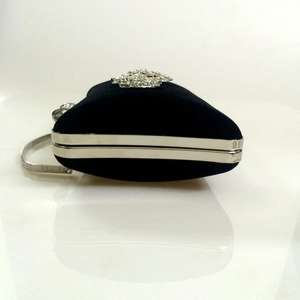 Detail of a heart-shaped black velvet evening bag with silver metal trim and rhinestones