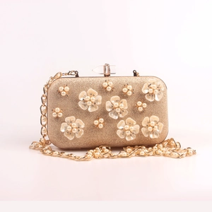 Detail of evening bag with pearl flowers, gold glitter material and crystal clasp