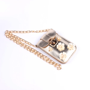 Detail der goldenen Mini-Tasche mit weißen 3D-Blüten, Perlen und goldener Kette