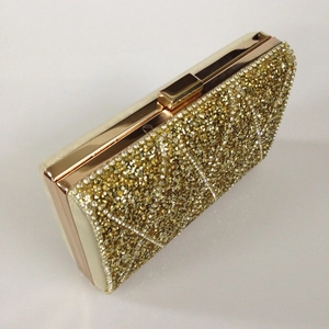 Detail of golden rectangle evening clutch bag with quilted rhinestone pattern and metal frame