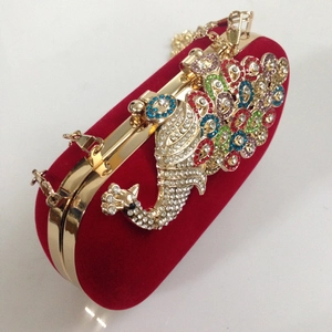 Detailed macro of red velvet clutch bag with multicolored rhinestone peacock pattern