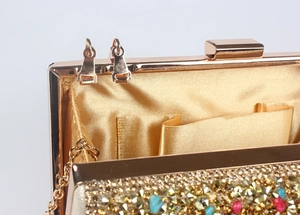 Detail of gold evening clutch showing rhinestone exterior, satin lining and metal chain