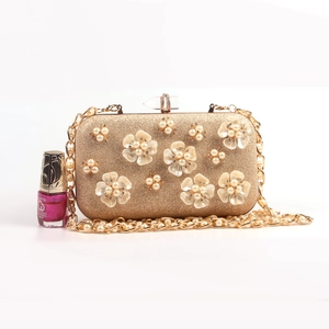 Detail of luxury gold evening clutch bag with 3D pearl flowers and chain strap