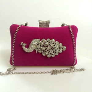 Detail of rose red velvet evening clutch featuring a sparkling rhinestone peacock motif