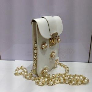 Detail der perlweißen Leder-Mini-Umhängetasche mit Blumenakzenten und Kettenriemen