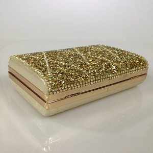 Close-up of golden evening clutch bag featuring striped rhinestone embellishments