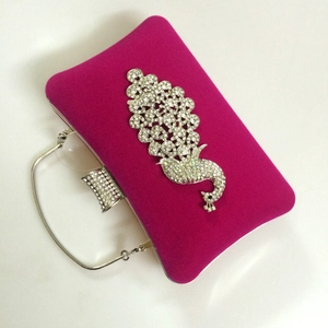Detail of velvet evening clutch bag featuring a luxurious rhinestone peacock ornament
