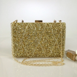 Macro view of crystal rhinestones and golden chain on a rectangular evening clutch bag