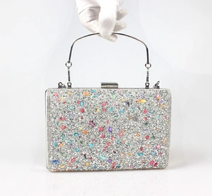 Detail of silver sequined evening clutch with colorful stones and metal handle