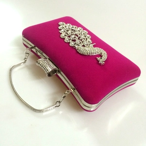 Close-up of rose velvet evening clutch with sparkling peacock rhinestone embellishment