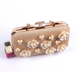 Macro view of champagne gold evening clutch with 3D pearl flowers and crystal clasp