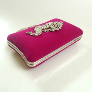 Detail of rose red velvet evening clutch with a sparkling crystal peacock ornament