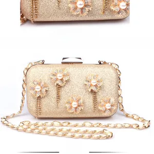 Close-up of golden evening clutch with diamond flowers, pearls and elegant fringe