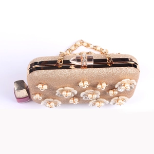 Detail of evening clutch featuring 3D pearl flowers and sequins with gold metal frame