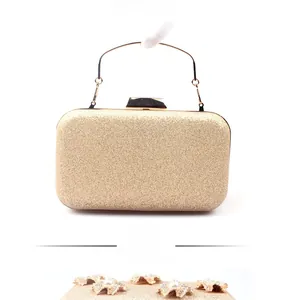 Back view of gold sequined clutch bag with metal handle and elegant pearl flower tassels