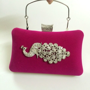 Detail of rose red velvet evening bag with crystal peacock design and metal handle