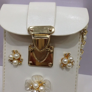 Detail der weißen Ledertasche mit Perlenblumen-Verzierung und goldenem Verschluss