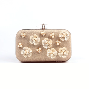 Macro view of champagne gold evening bag with 3D enamel flowers and pearl details