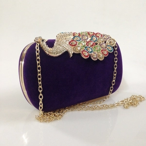 Macro detail of purple velvet clutch with colorful peacock rhinestone clasp and gold chain