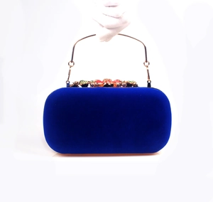 Detailed view of blue velvet evening clutch with golden handle and colorful floral gemstone