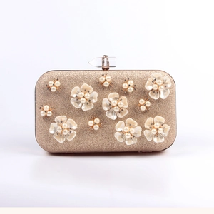 Detail of champagne gold evening bag with 3D white petals, pearls, and a crystal clasp