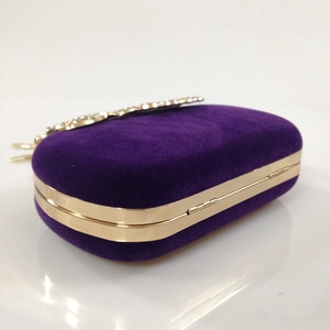 Close-up of deep purple velvet evening clutch featuring gold frame and crystal clasp