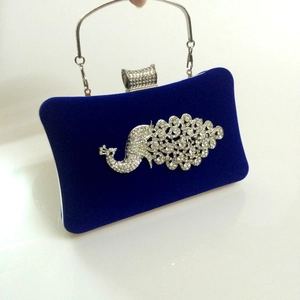 Detailed close-up of velvet evening bag featuring crystal peacock and silver handle