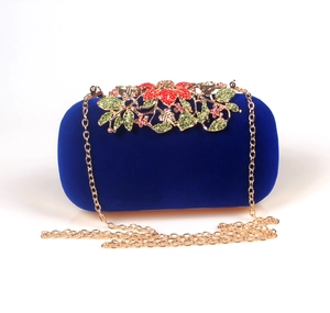 Detailed view of royal blue velvet clutch featuring ornate golden floral rhinestone clasp
