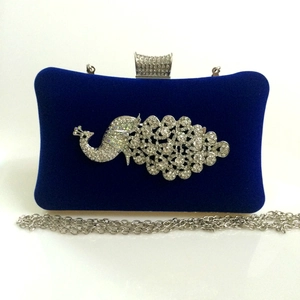 Detail of royal blue velvet evening bag featuring crystal peacock and silver chain
