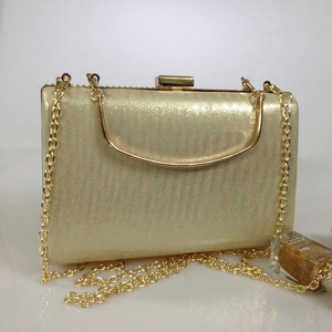 Close-up of sparkling gold glitter evening clutch bag with metal handle and chain