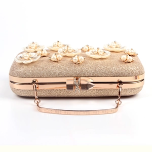 Detail of champagne gold evening bag featuring pearl flowers and sparkling glitter finish